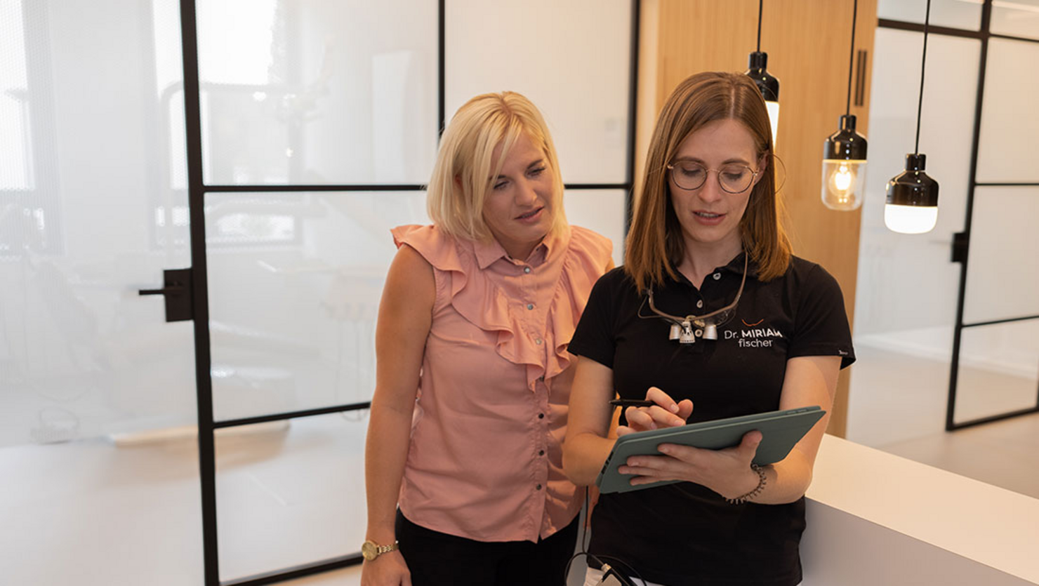 Dentist Dr. Miriam Fischer shows something to a patient on her tablet